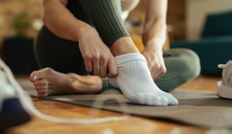 Close-up of sportswoman wearing white socks while preparing for workout at home.